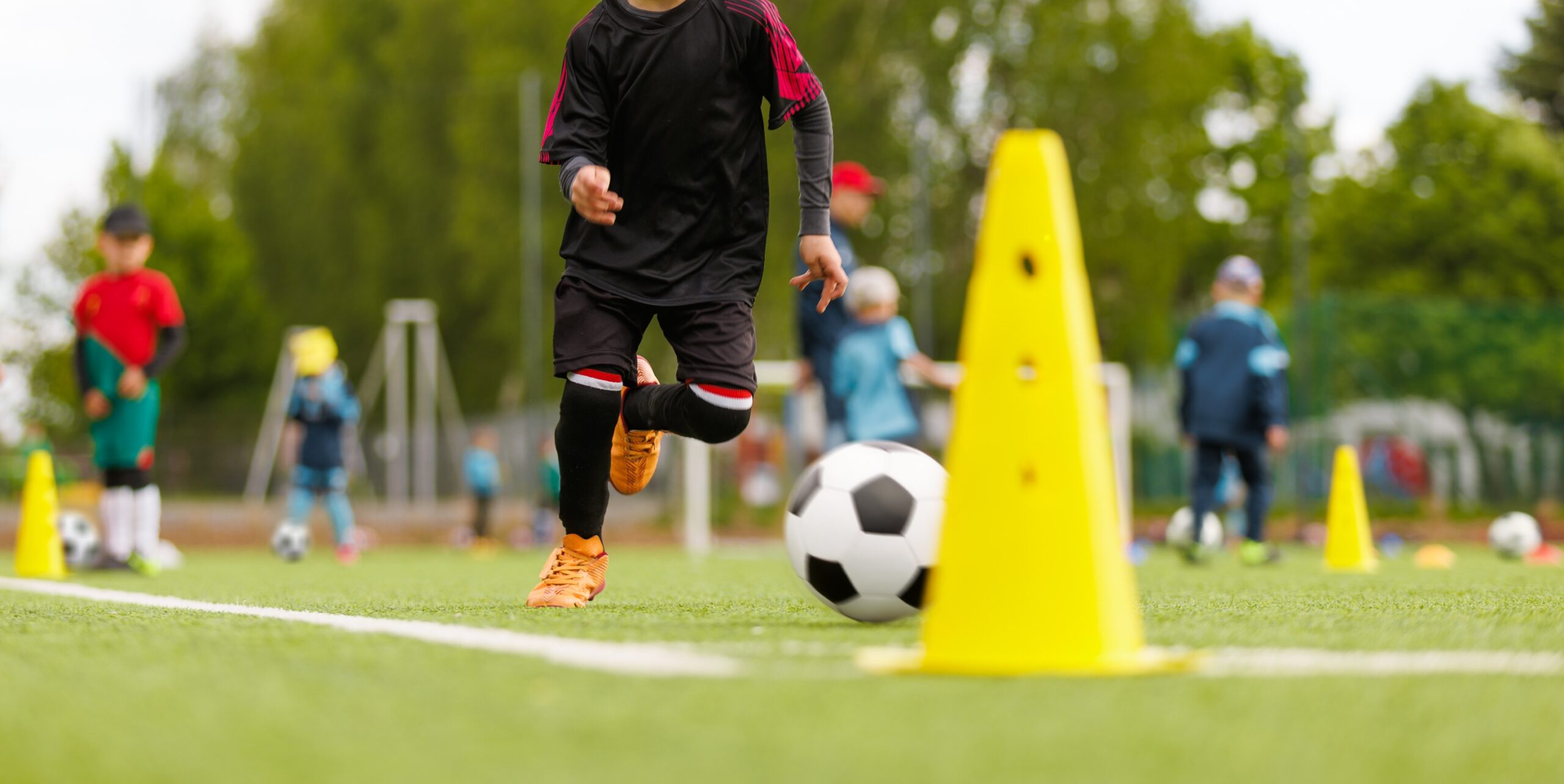 Grupa przedszkolaków rozpoczynająca przygodę ze sportem od najmłodszych lat podczas zajęć z piłki nożnej dla dzieci.